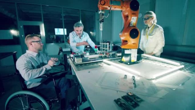 坐在轮椅上的工程师和同事正在现代实验室中对机器人进行编程