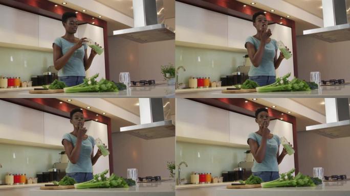 微笑的非洲裔美国迷人女人在厨房品尝自制冰沙