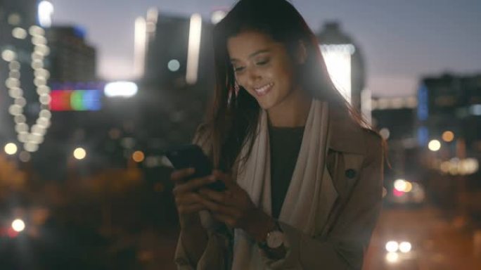 4k视频片段，一名妇女晚上在城市的屋顶上使用手机时使用手机