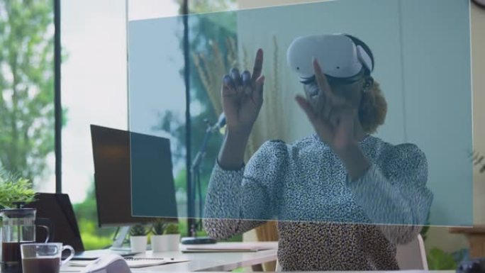 女人看着投影屏幕坐在桌子上戴着VR耳机与AR技术互动