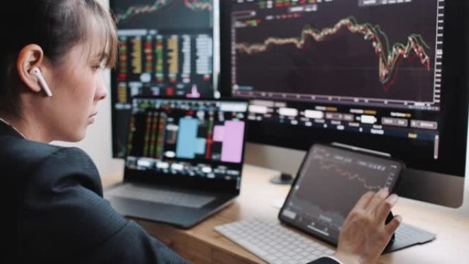 女商人投资者正在办公室的数字平板电脑上交易股票