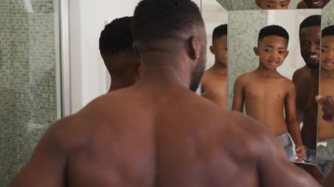 非裔美国人父子一起在镜子里展示自己的肌肉
