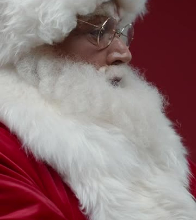 红色背景上的圣诞老人的垂直特写镜头，他记得他需要戴上红色的防护面罩