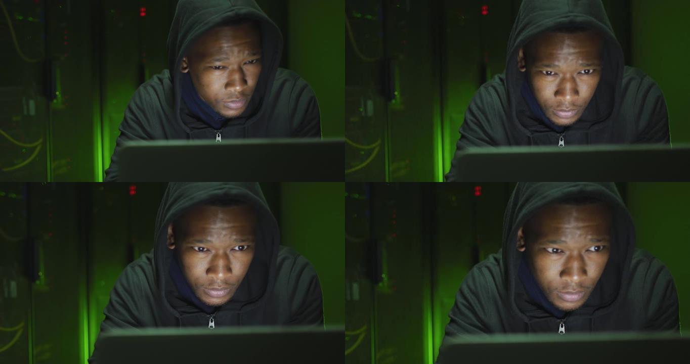 非裔美国男性计算机黑客在商务服务器机房使用笔记本电脑