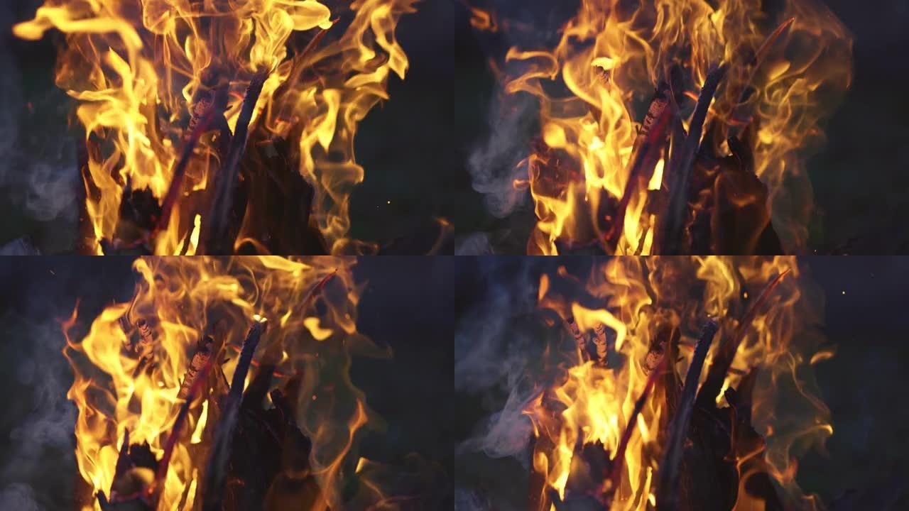 慢动作4k拍摄木柴在火中燃烧。明亮的橙色篝火火焰和白烟。晚上的篝火特写