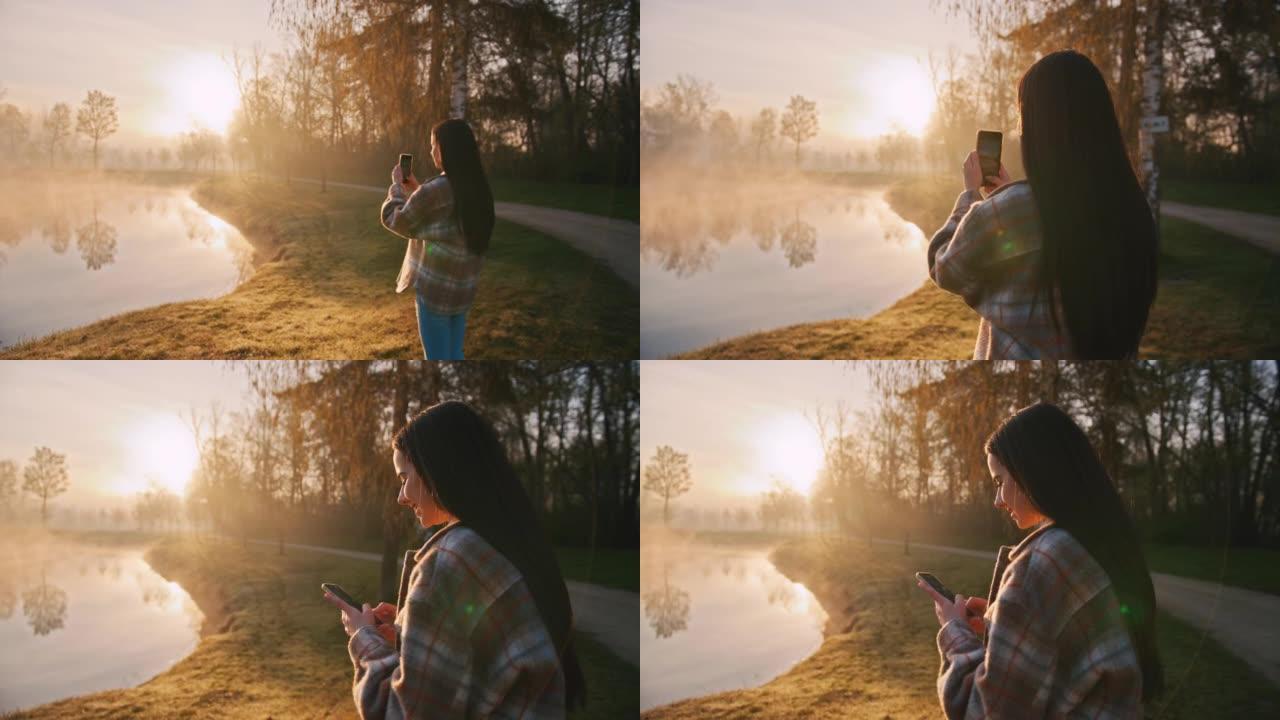 年轻女子站在岸上拍摄雾湖的照片