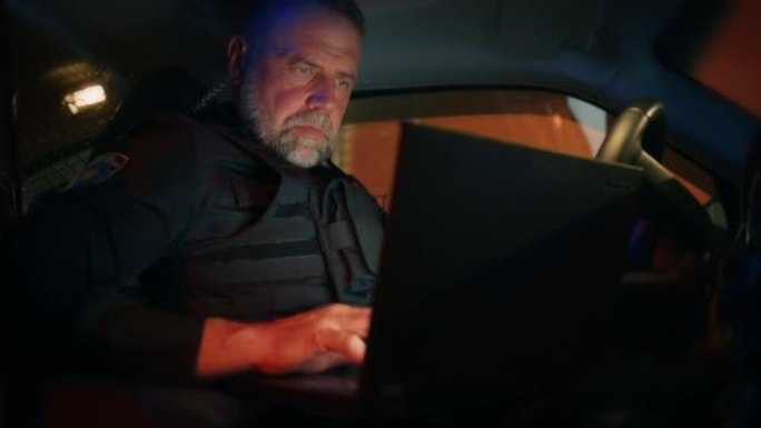 在警察交通巡逻警车内:值班的白人男性警察使用笔记本电脑检查犯罪嫌疑人的背景，执照号码，执照和登记。打