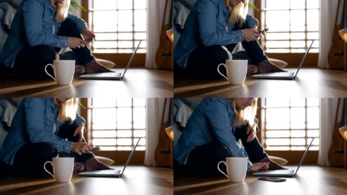 坐在家里地板上的DS女人使用笔记本电脑和智能手机
