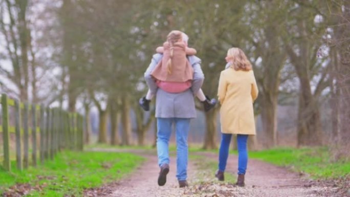 祖父给孙女Piggyback与祖母一起穿越冬季乡村