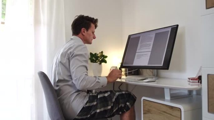 DS男子在家在客厅里穿着衬衫，领带和短裤在计算机上工作