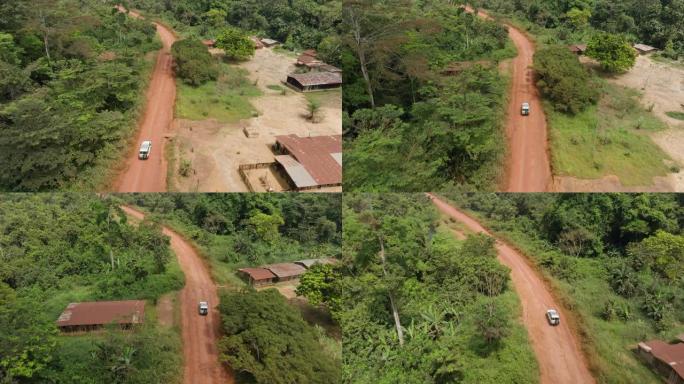 在非洲中部热带雨林的伐木公路上驶过一个小村庄的车辆的鸟瞰图