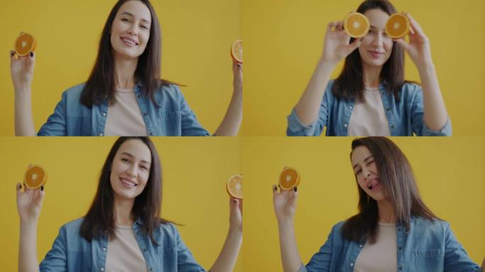 幸福女人的肖像玩捉迷藏，橘子微笑着在黄色背景上眨眼