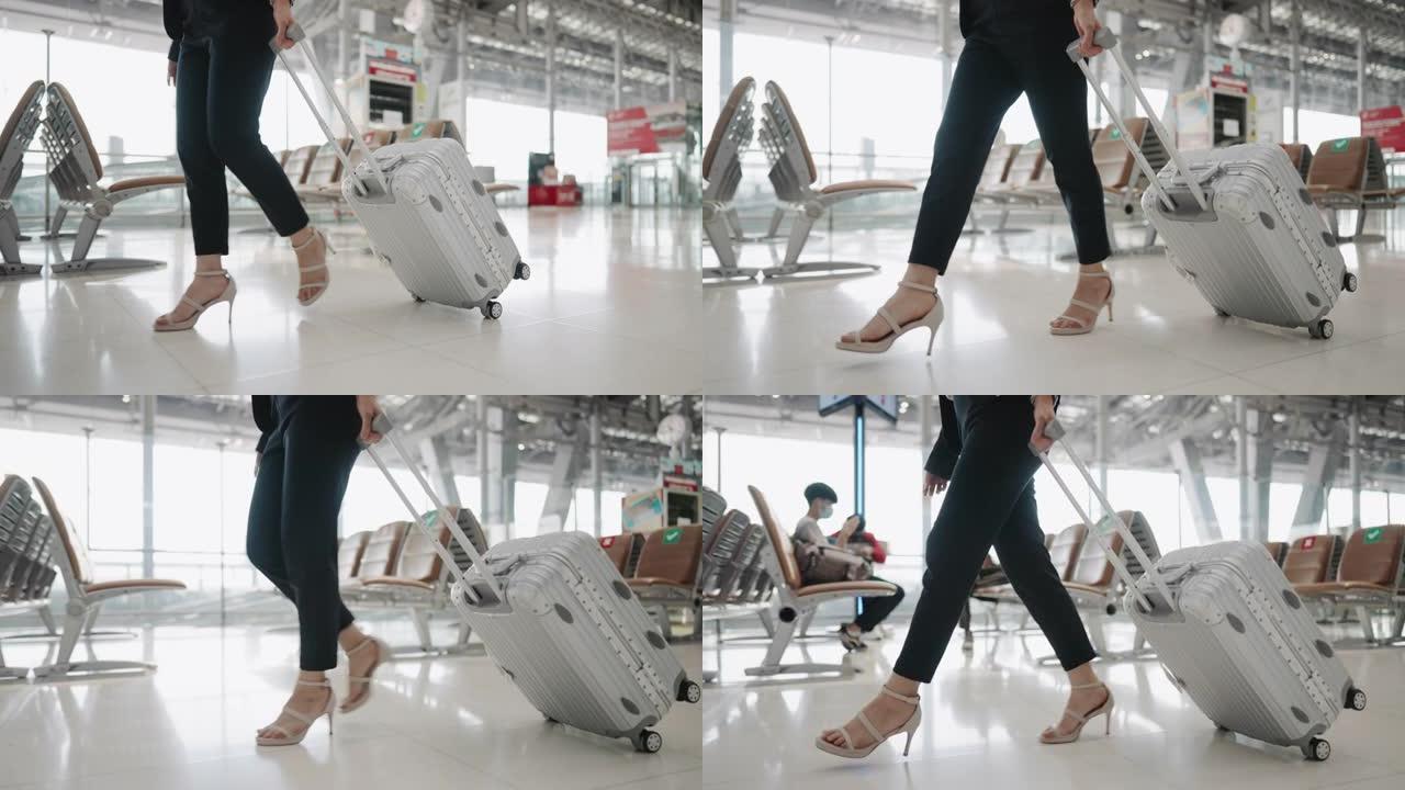 穿着高跟鞋的女人的腿带着带轮行李在机场行走