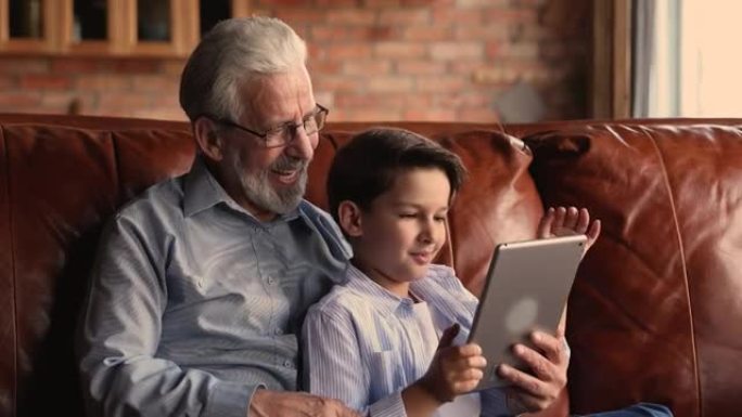 60多岁的老人与孙子一起使用数字计算机平板电脑。