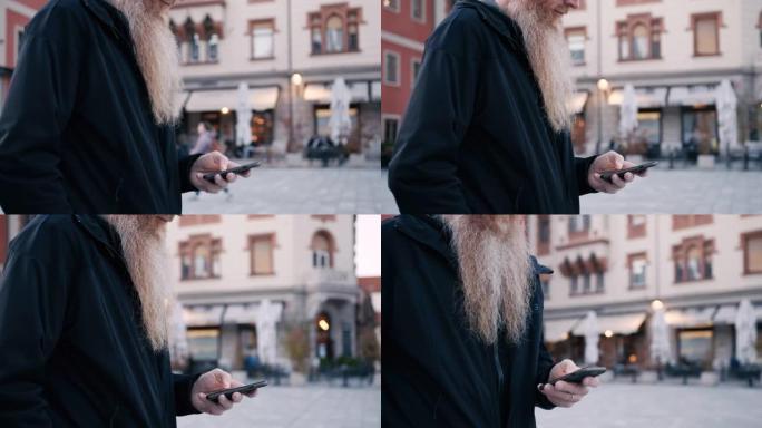 在城市散步时，留着长胡须的男人使用智能手机
