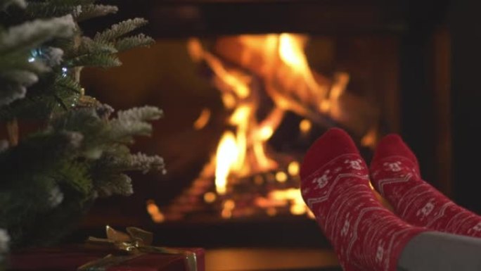 特写: 女人的脚穿着红色袜子，壁炉旁有圣诞节图案