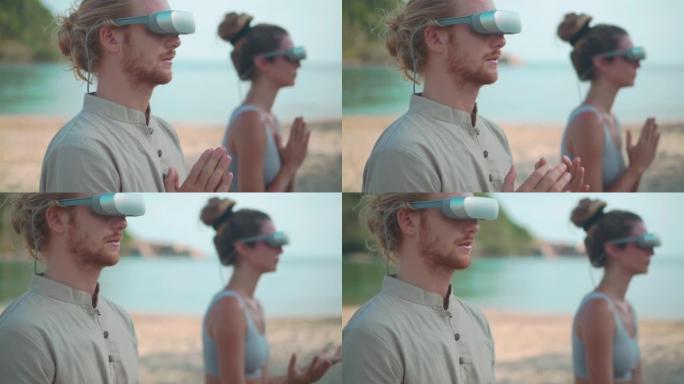 25-29岁的拉丁美洲和西班牙裔年轻夫妇戴着技术虚拟现实耳机，早上在夏日海滩上的户外练习瑜伽。Met
