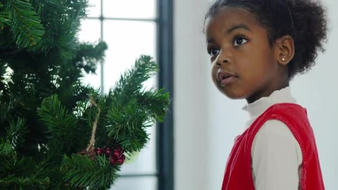 幸福的肖像给女孩非洲民族年龄3岁的威林红色服装准备和装饰圣诞树。圣诞精神概念。