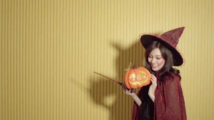 一个穿着女巫服装的女孩拿着橙色南瓜桶的肖像