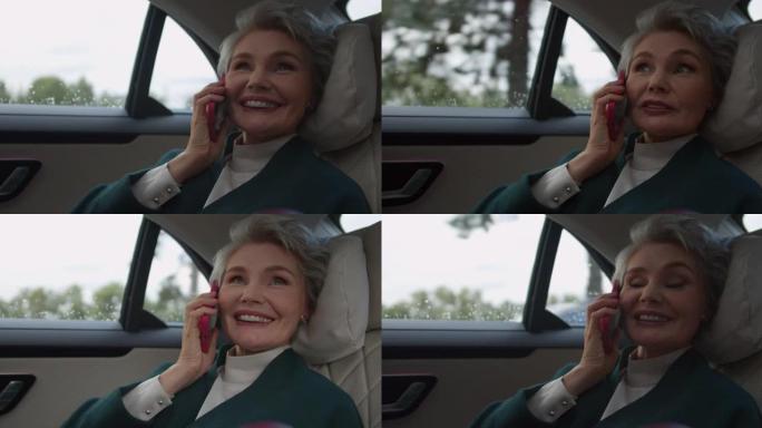 一位发型时尚的白发女商人在粉红色的电话上愉快地聊天，坐在汽车上担任vip乘客