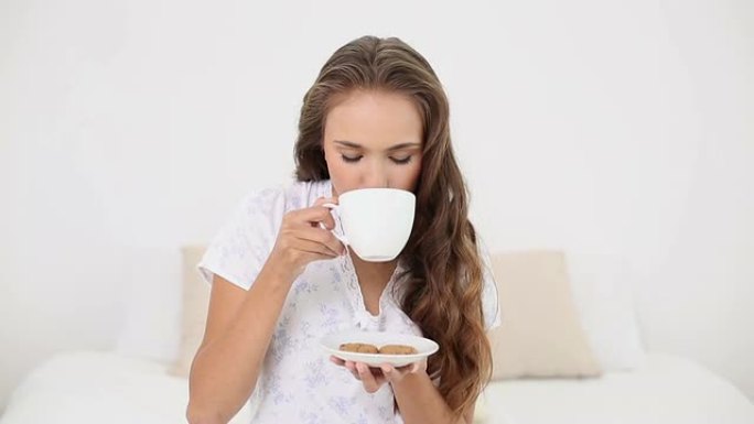 年轻女子喝一杯茶和饼干