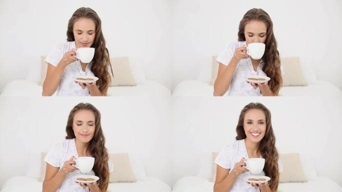 年轻女子喝一杯茶和饼干