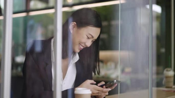 亚洲妇女在咖啡店用手机发短信