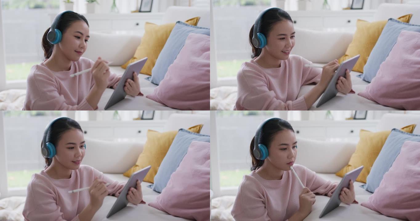 年轻的亚洲女孩在数字平板电脑上在家听学习在线播客