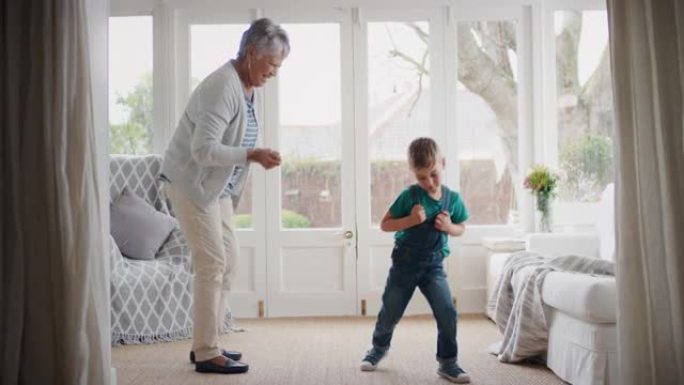 快乐的小男孩和祖母跳舞有趣的奶奶和孙子在家庆祝家庭周末跳舞