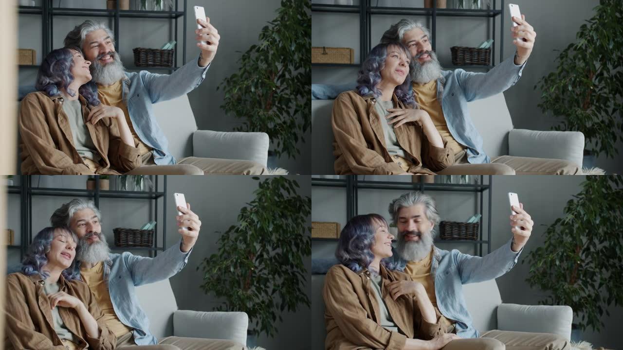 幸福的夫妻聊天和挥手在家用智能手机进行在线视频通话