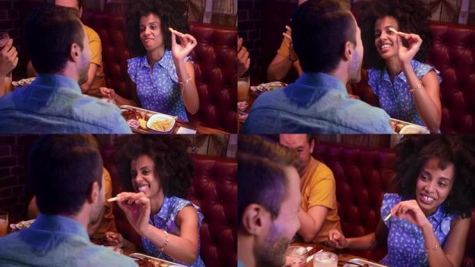 非裔美国妇女在复古餐厅向朋友喂薯条