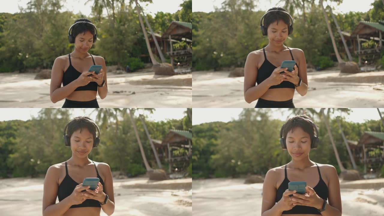 穿着运动服的女人在海滩上使用电话