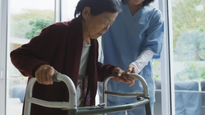 微笑的亚洲女医生帮助高级女患者使用步行框架行走
