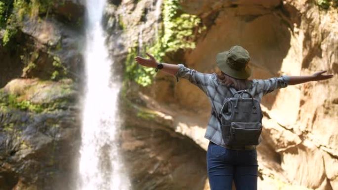 女人徒步旅行到绿色森林的瀑布