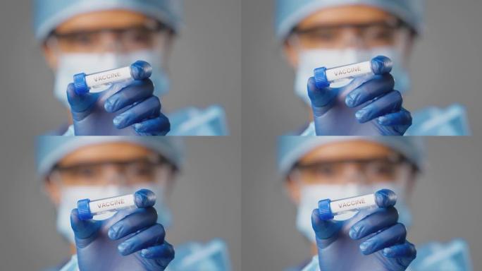 女性实验室研究人员穿着个人防护用品，手持标有疫苗的试管的特写