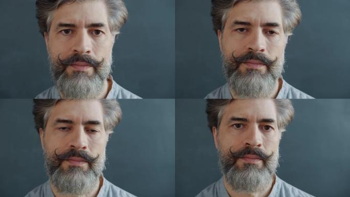 灰发大胡子男子用严肃的脸看着相机的特写慢动作肖像