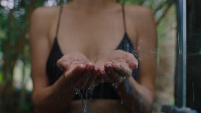 女人在淋浴抓水在手中享受清新的清洁淋浴在大自然的户外