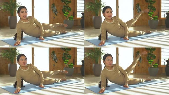 仍在射击: 亚洲女子在家锻炼，在前臂上进行普拉提侧腿举