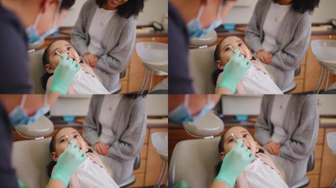 一个年轻可爱的女孩在牙医和她的妈妈一起检查牙齿。可爱的小牙疼的孩子去看口腔专业人员在她的定位牙科检查