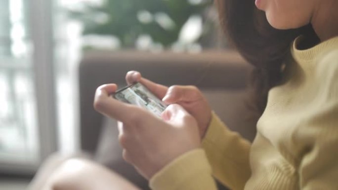 特写亚洲女人手在客厅玩智能手机数码小工具在线游戏
