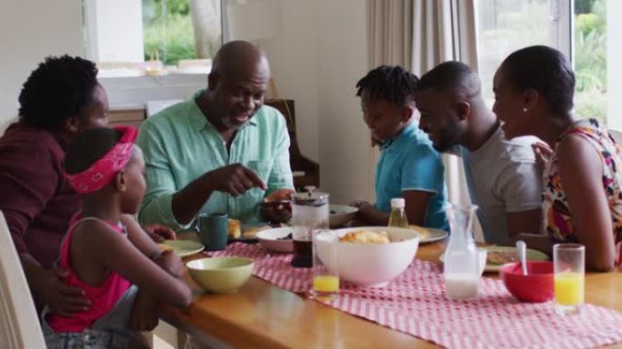 三代非洲裔美国家庭看着智能手机，在家一起吃早餐