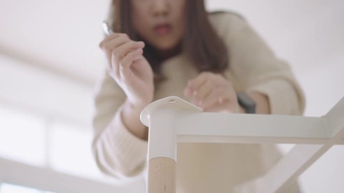 亚洲女人拧DIY桌子底座的螺栓