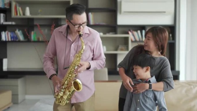 亚洲华裔父亲喜欢在周末闲暇时间与家人在家演奏萨克斯风