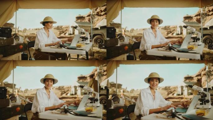 考古挖掘地点: 伟大的女性考古学家的肖像进行研究，使用笔记本电脑，微笑着看着相机，同时拿着化石遗骸或