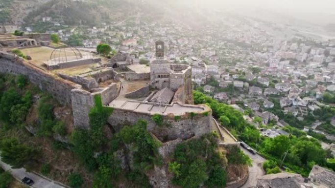 在阿尔巴尼亚日落时在吉罗卡斯特要塞城堡周围飞行。旧的石头房子，山谷和山脉在背景。Gjirokastr