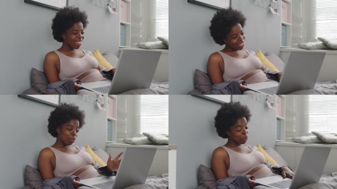 年轻的黑人妇女在床上的笔记本电脑上聊天