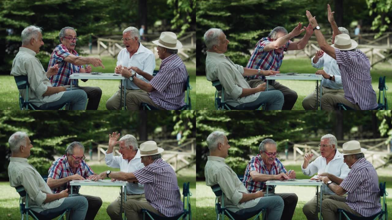 一群年长的男性朋友一起在公园里打牌，享受户外的夏日天气。老年玩家获得幸运的连胜。富有表现力的人庆祝胜