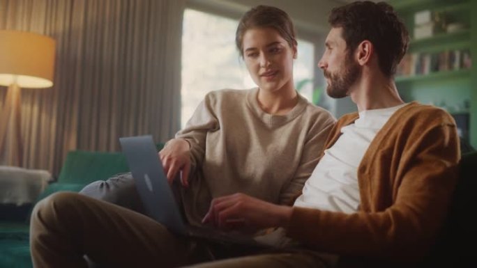 夫妇坐在公寓的沙发上时使用笔记本电脑。男女朋友聊天，在网上购物，选择在线订购的产品，在流媒体服务上观