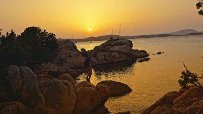 意大利撒丁岛日落时在岩石上行走的人的景色。