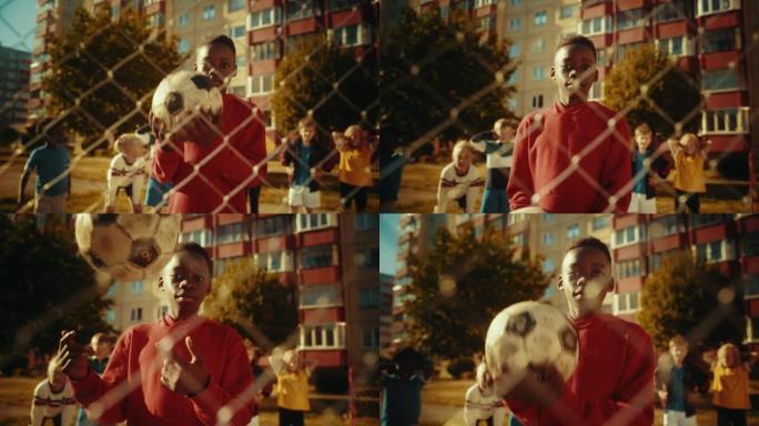 一个年轻英俊的黑人男孩在看着相机微笑时投掷并抓住足球的肖像。运动的非洲孩子梦想成为一名职业足球运动员